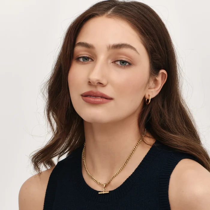 Model wearing gold curb chain fob necklace with T-bar pendant and navy top