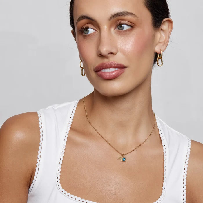 Gem Initial Necklace with initial and aquamarine birthstone worn on model in gold