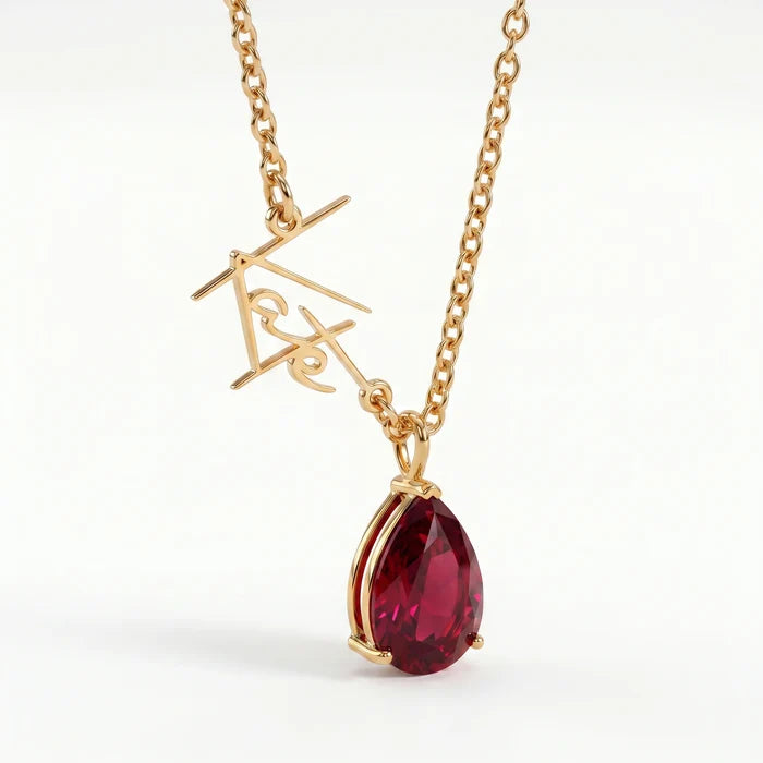 Script name necklace with pear-cut ruby birthstone charm close-up in 18k gold plated steel